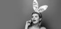 Easter banner with bunny woman. Easter bunny girl. Portrait shocked young woman with mobile phone isolated over pink