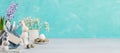 Easter banner. Eggs, ceramic bunnies, flowers, gift bag, blank note on turquoise. Copy space. Royalty Free Stock Photo