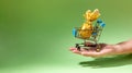 Easter banner. Female hand holding small decorative supermarket basket with golden wrapped Easter egg. Holiday delivery. Royalty Free Stock Photo