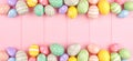 Easter banner with double border of pastel Easter Eggs over a pink wood background with copy space Royalty Free Stock Photo