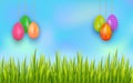 Easter banner with set of colorful hanging eggs and copy space on background with blue sky and grass. Royalty Free Stock Photo