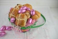 Easter basket filled with with fresh hot cross buns and shiny pink eggs