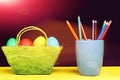 Easter basket full of colourful eggs and mug with pencils