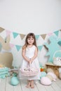 Easter! Beautiful little girl in a white dress with Easter eggs and a basket on a bright Easter scenery. Easter location, decorati