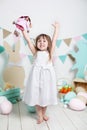 Easter! Beautiful little girl in a white dress rejoices at the holiday. Many different colorful Easter eggs, colorful interior. fa