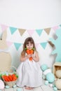 Easter! Beautiful little girl in white dress sitting with Easter bunnies and carrots. Rabbit, colorful eggs. Many different colorf