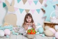 Easter! A beautiful little girl in a white dress is sitting with an Easter basket and a carrot. Rabbit, colorful Easter eggs. East Royalty Free Stock Photo