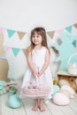 Easter! Beautiful little girl in a white dress is standing with an Easter basket. Many different colorful Easter eggs, colorful in
