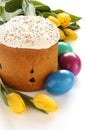 Easter bread, colorful eggs and yellow tulips on white background Royalty Free Stock Photo