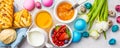 Easter Breakfast table, top view. Colored eggs, flowers, buns, milk, juice and jam, white background Royalty Free Stock Photo