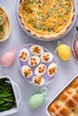 Easter brunch on large table with spiral sliced ham, quiche, deviled eggs and hot cross buns