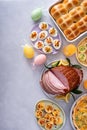 Easter brunch on large table with spiral sliced ham, quiche, deviled eggs and hot cross buns