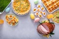 Easter brunch on large table with spiral sliced ham, quiche, deviled eggs and hot cross buns