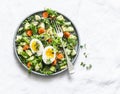 Easter brunch quinoa, eggs, avocado, cucumber, carrot salad on light background, top view. Healthy vegetarian food concept