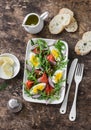 Easter brunch salad. Smoked salmon, eggs, arugula, red onion, olive oil, lemon dressing salad on wooden background, top view