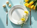 Easter brunch table setting with white plate, yellow tulips, wildflowers, eggs, fork and knife. Minimalist spring celebration Royalty Free Stock Photo