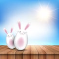 Easter bunnies on a wooden table looking out to a sunny sky Royalty Free Stock Photo