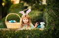 Easter bunny child hunting eggs with easters basket outdoors on Happy Easter day.