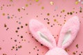 Easter bunny concept. Toy rabbit`s ears with stars confetti on pastel pink background. Flat lay, top view, copy space