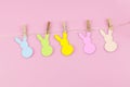 Easter bunny craft paper garland on pink background. DIY holiday handicraft decoration of colorful rabbits. Top view, cutout