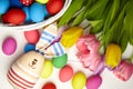 Easter bunny doll and Easter eggs in basket and spring colorful flowers on white wooden table Royalty Free Stock Photo