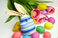Easter bunny doll and Easter eggs in basket and spring colorful flowers on white wooden table Royalty Free Stock Photo