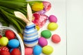 Easter bunny doll and Easter eggs in basket and spring colorful flowers on white wooden table Royalty Free Stock Photo