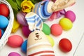 Easter bunny doll and Easter eggs in basket and spring colorful flowers on white wooden table Royalty Free Stock Photo