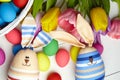 Easter bunny doll and Easter eggs in basket and spring colorful flowers on white wooden table Royalty Free Stock Photo