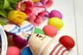 Easter bunny doll and Easter eggs in basket and spring colorful flowers on white wooden table Royalty Free Stock Photo