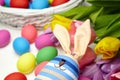 Easter bunny doll and Easter eggs in basket and spring colorful flowers on white wooden table Royalty Free Stock Photo