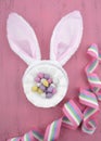Easter bunny ears with Easter eggs on pink wood - vertical