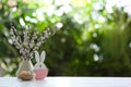 Easter bunny figure and dyed eggs on wooden table against blurred green background. Space for text Royalty Free Stock Photo
