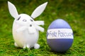 Easter bunny figures and purple easter egg with spanish text, happy easter