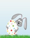 Easter bunny holding a large decorated egg. Rabbit on the grass. Greeting card