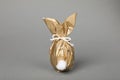 Easter bunny made of shiny gold paper and egg on grey background