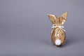 Easter bunny made of shiny gold paper and egg on grey background. Space for text