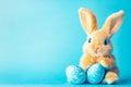 Easter bunny rabbit with blue painted egg on blue background. Easter holiday concept Royalty Free Stock Photo