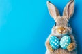 Easter bunny rabbit with blue painted egg on blue background. Easter holiday concept Royalty Free Stock Photo