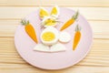 Easter bunny rabbit and chicken eggs children kids food concept. With carrot on rosy pink plate. Wooden background Royalty Free Stock Photo