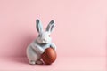 Easter bunny rabbit hold painted egg on pink background.