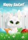 Easter bunny siting on a grass among Easter eggs, white wooden fence