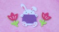 Easter bunny and tulips made from felt laying on a pink background with copy space