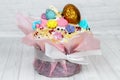 Easter cake with golden and colorful eggs on the top, sophisticatedly decorated, candies, sugar flowers, icing, meringue, and pink