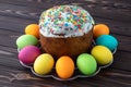 Easter cake and painted colorful eggs on dark wooden boards. Paschal gift card. Food background