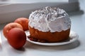 Easter cake is watered with white glaze and sprinkled with poppy seeds on top. Three brown chicken eggs dyed with onion skins. Clo