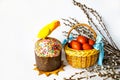 Easter cake, a wicker basket with brown Easter eggs, willow twigs and a lovebird parrot of bright festive yellow and red colors on