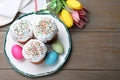 Easter cakes, painted eggs and tulips on wooden table, flat lay. Space for text