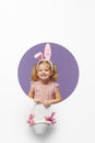 Easter card. Cute little child girl with bunny ears holding basket of Easter eggs. Child in a round hole circle in colored purple Royalty Free Stock Photo