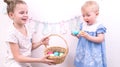 Easter celebration: The girl treats her younger sister with painted Easter eggs from a wicker basket.